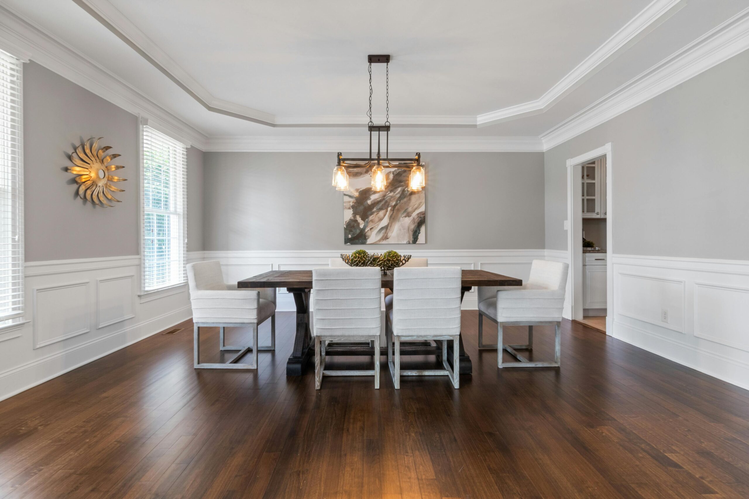 Bright dining room with modern furniture, featuring a wooden table and stylish lighting fixtures.
